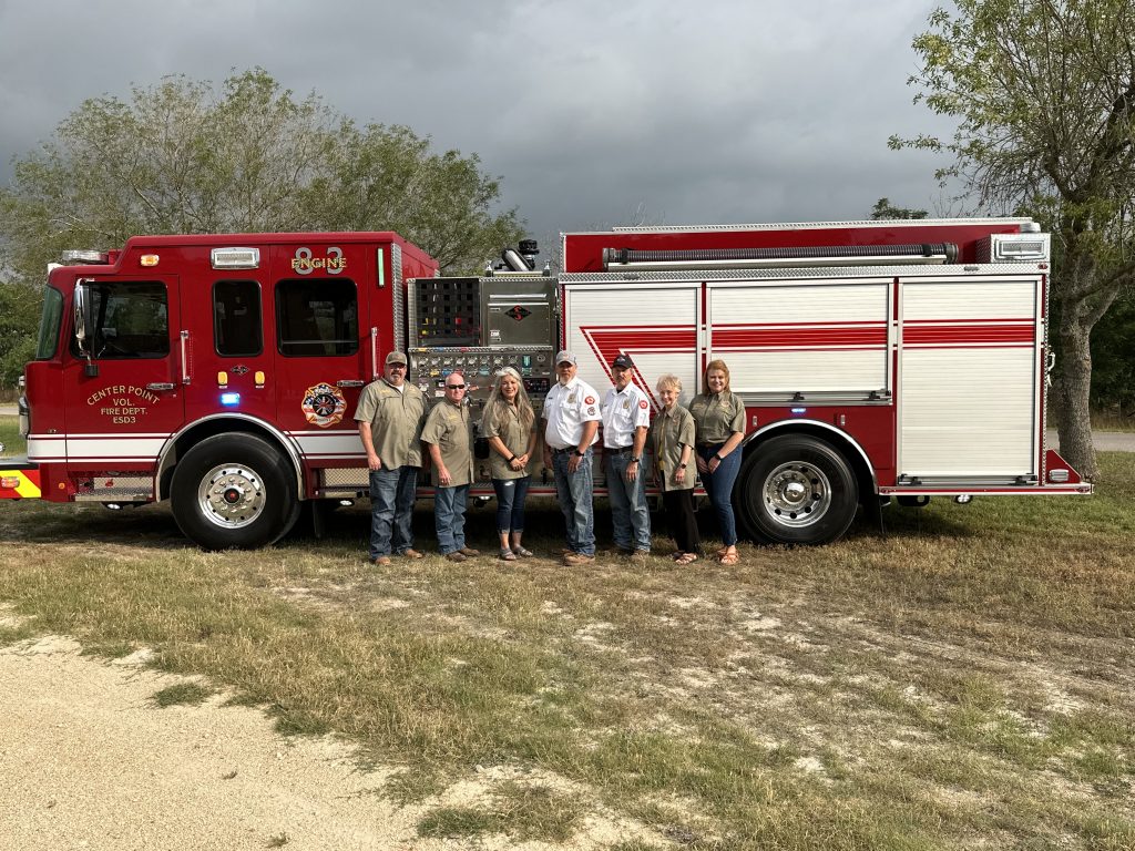 Team of firefighters posing on the side of a firetruck